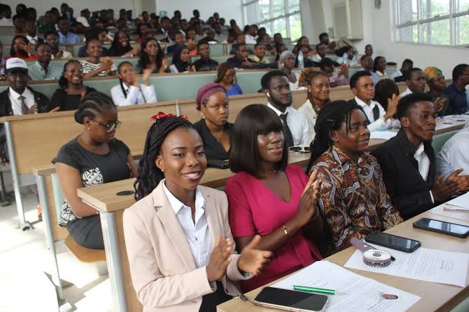 Nigerian students reading a university notice board together on campus